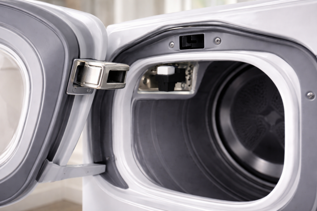 Dryer door partially open showing the latch and door switch area